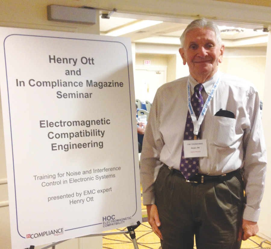 Henry Ott standing next to an In Compliance Magazine Seminar sign