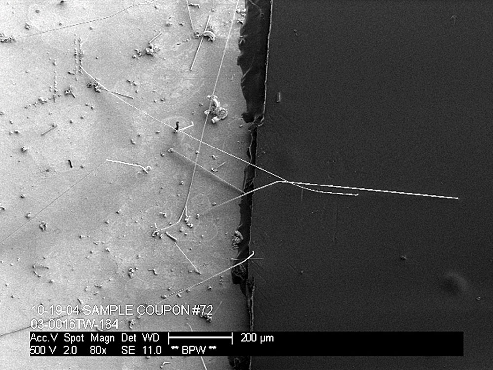Tin whisker formation between coated and uncoated surfaces