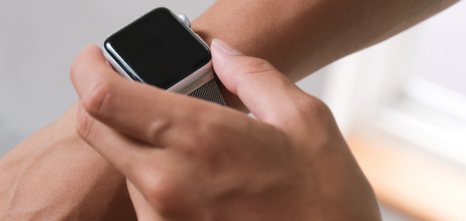 cropped view of a hand grasping an Apple Watch being warn on a wrist