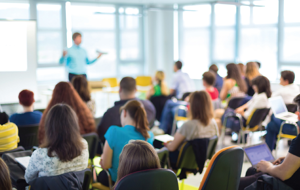 classroom full of students with teacher speaking at the front