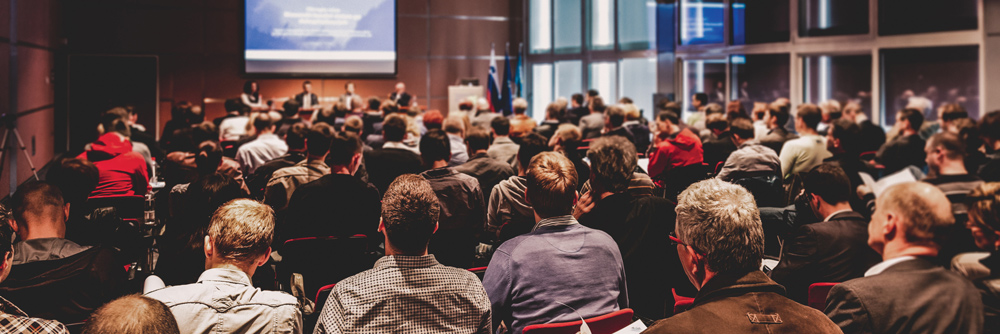 group of people listening to a speech at an event