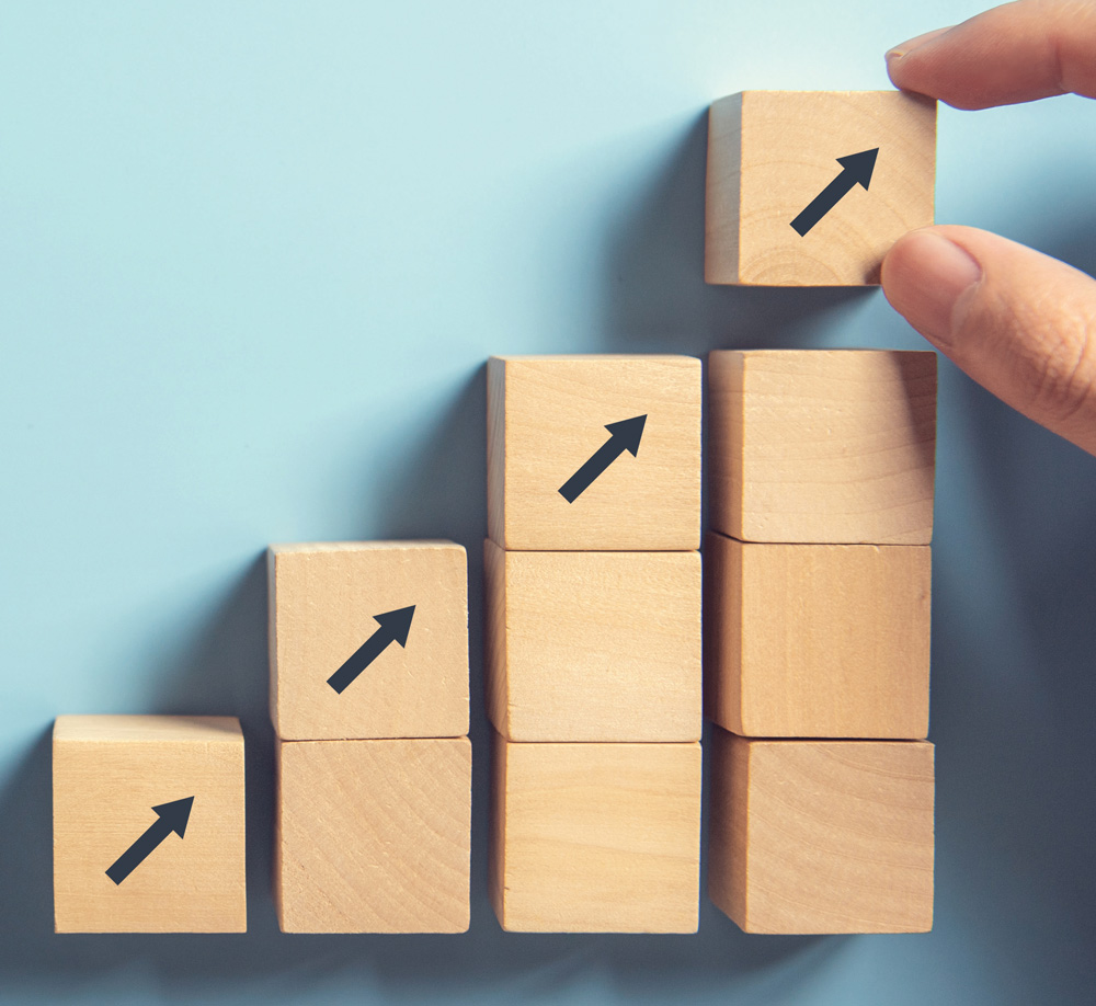 hand placing blocks in a staircase-like structure, with each block having an upward arrow