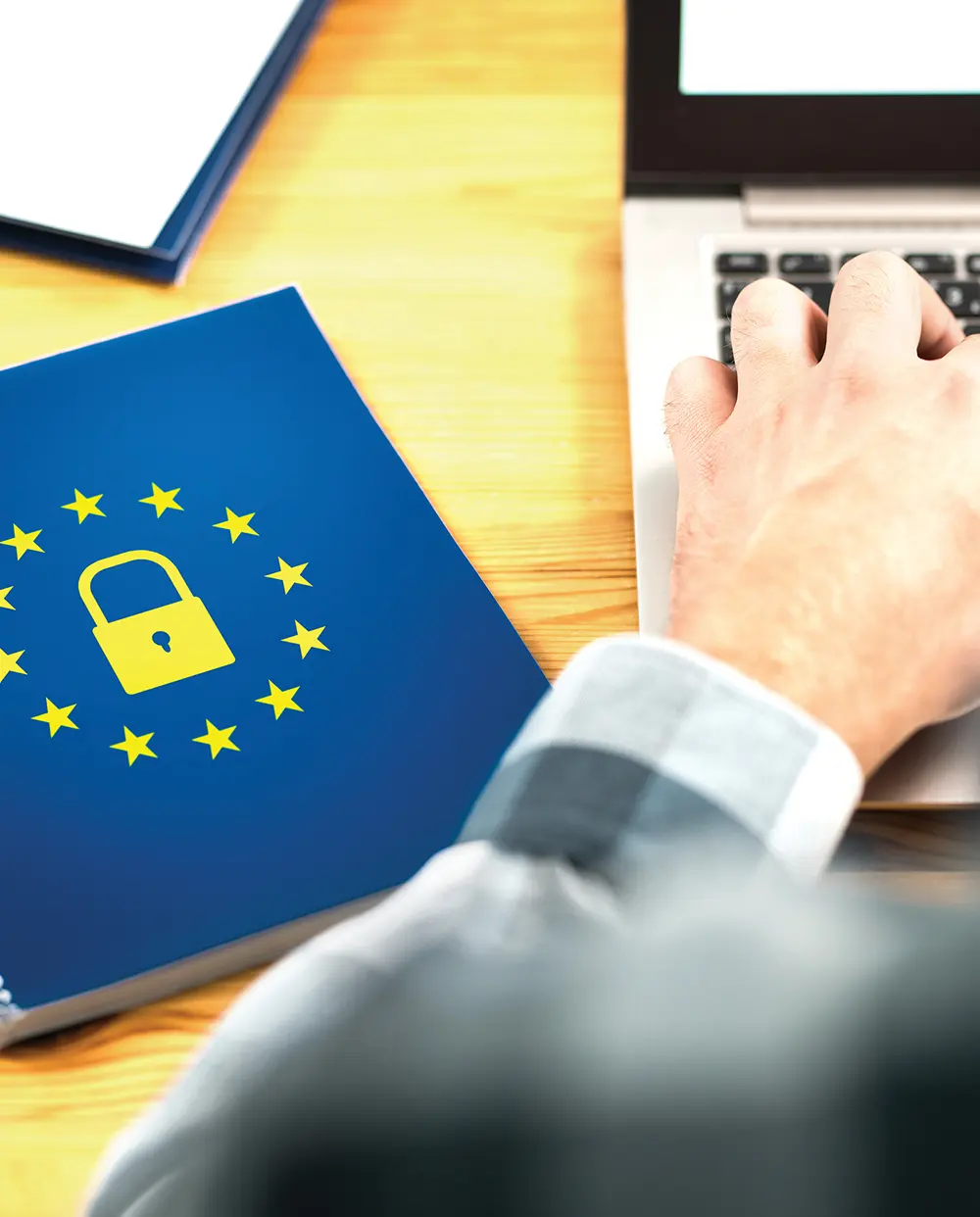 hand typing on laptop keyboard next to a blue spiral notebook with a yellow lock circled by yellow stars design