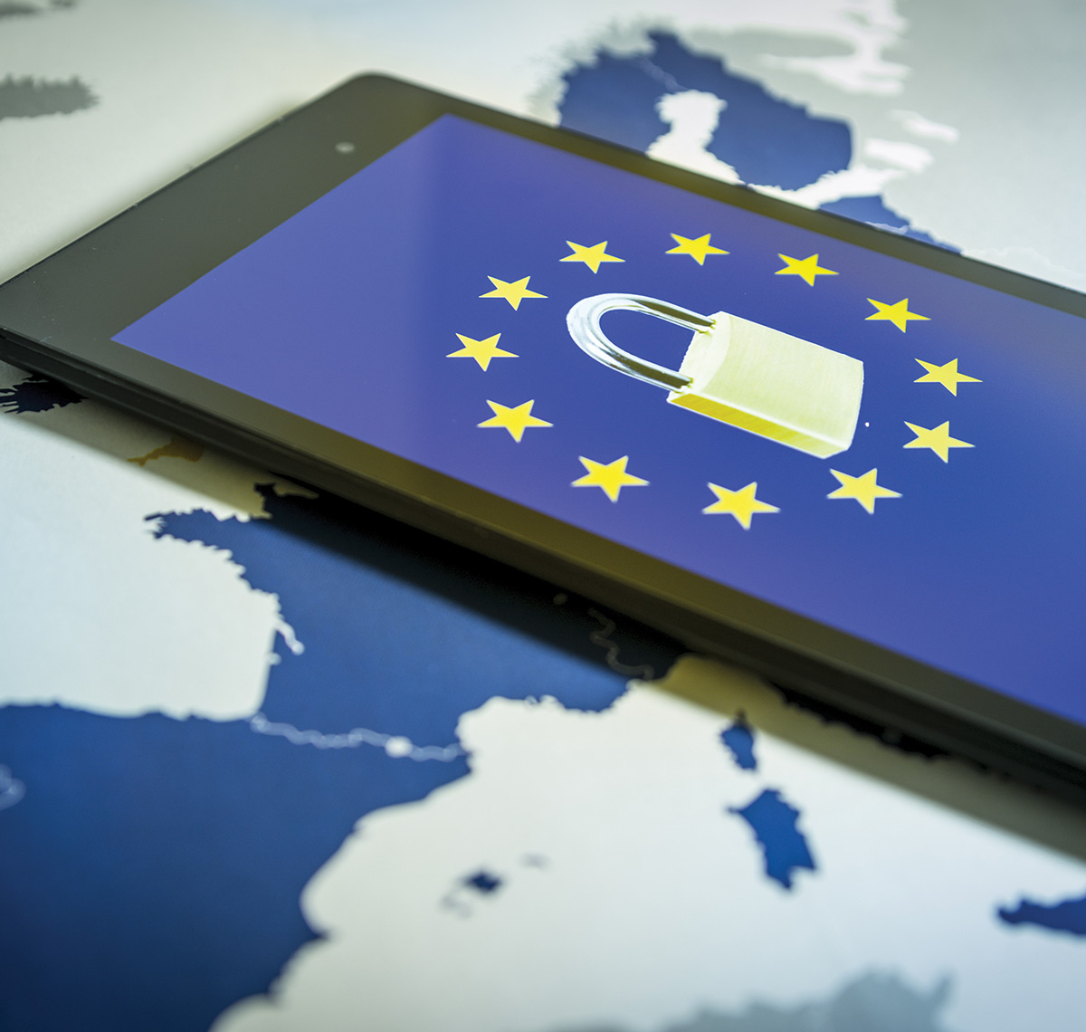 A tablet displaying a padlock icon surrounded by the European Union stars, resting on a map of Europe, symbolizing GDPR.