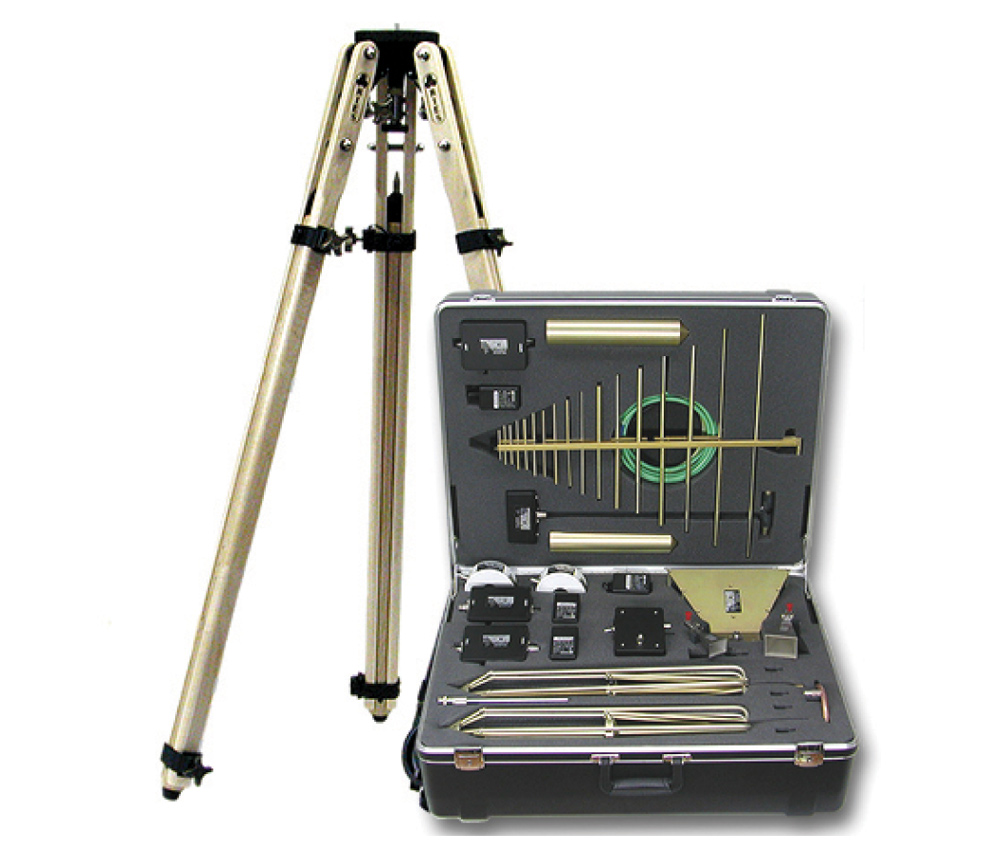 A tripod stand next to an open equipment case containing a set of brass antenna elements and probes for Electromagnetic Compatibility (EMC) testing.