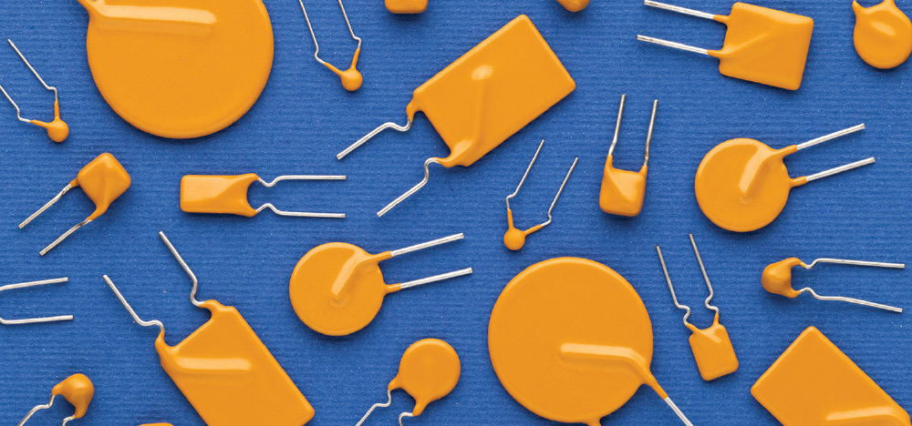 Top-down view of various orange disk and rectangular electronic capacitors scattered across a textured blue surface.
