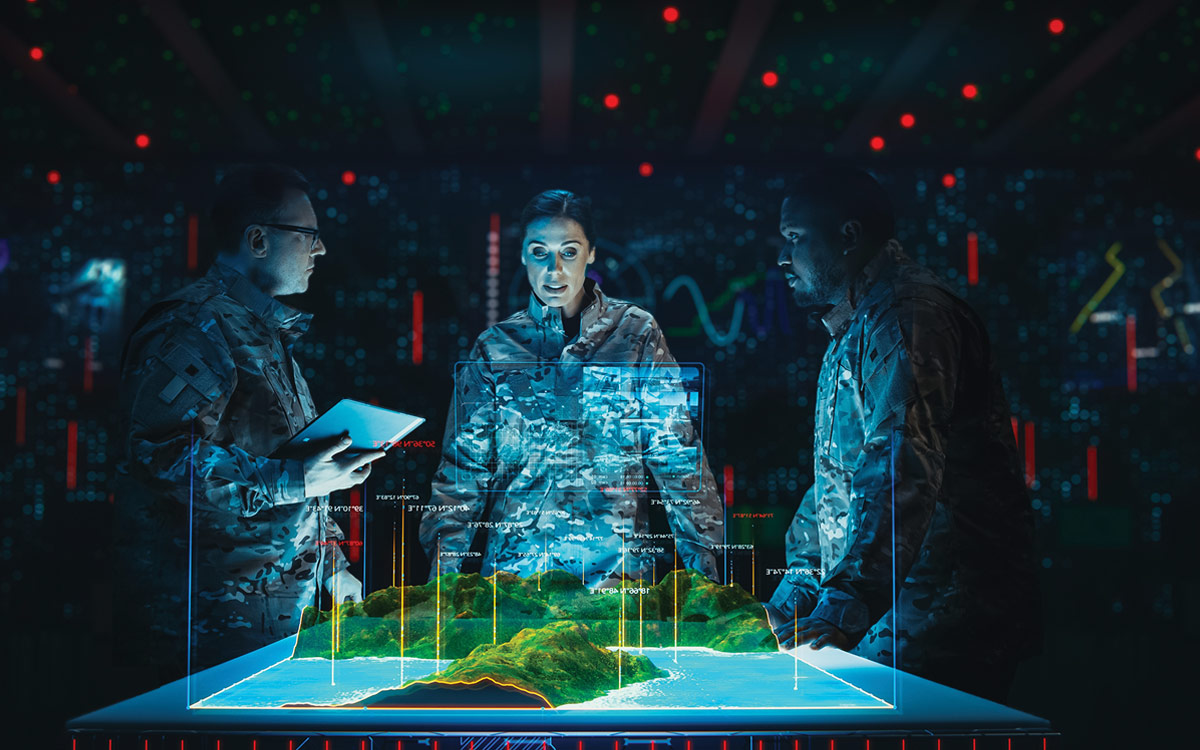 Three military personnel in a dark command center analyze a 3D holographic terrain map and signal data overlays.