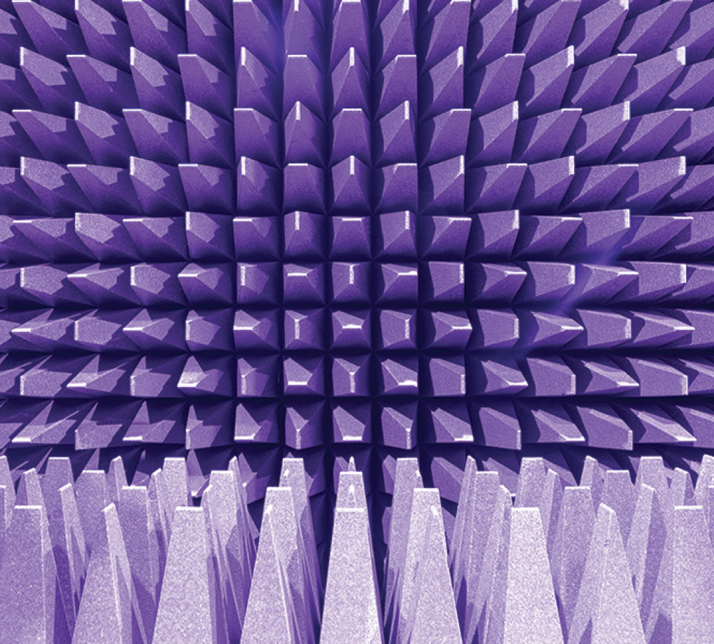 A symmetrical, close-up view of purple and grey pyramid-shaped acoustic foam panels inside an anechoic chamber, designed to absorb sound and electromagnetic waves.