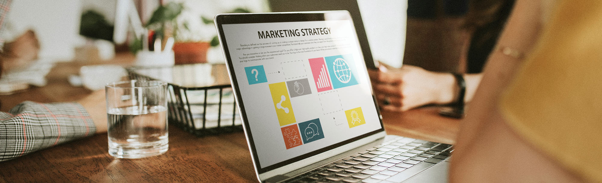 A laptop displaying a marketing strategy presentation sits on a conference table.