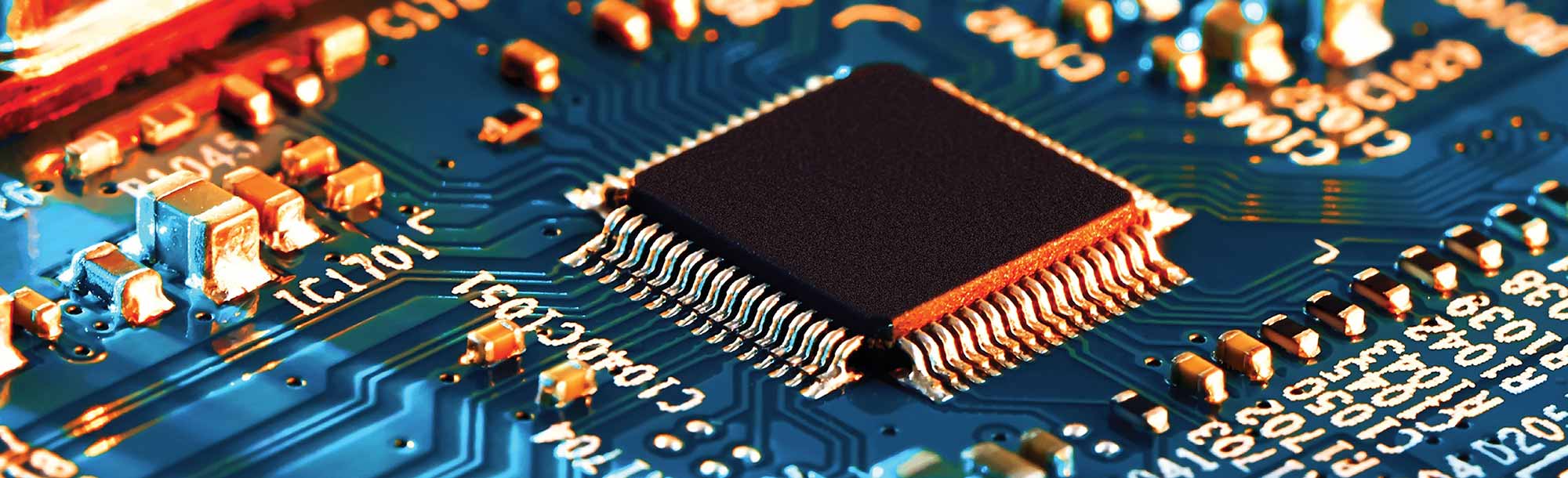 Close-up of a black microchip mounted on a blue printed circuit board.