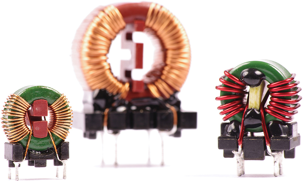 A studio macro shot of three toroidal inductors with copper wire windings mounted on pin headers