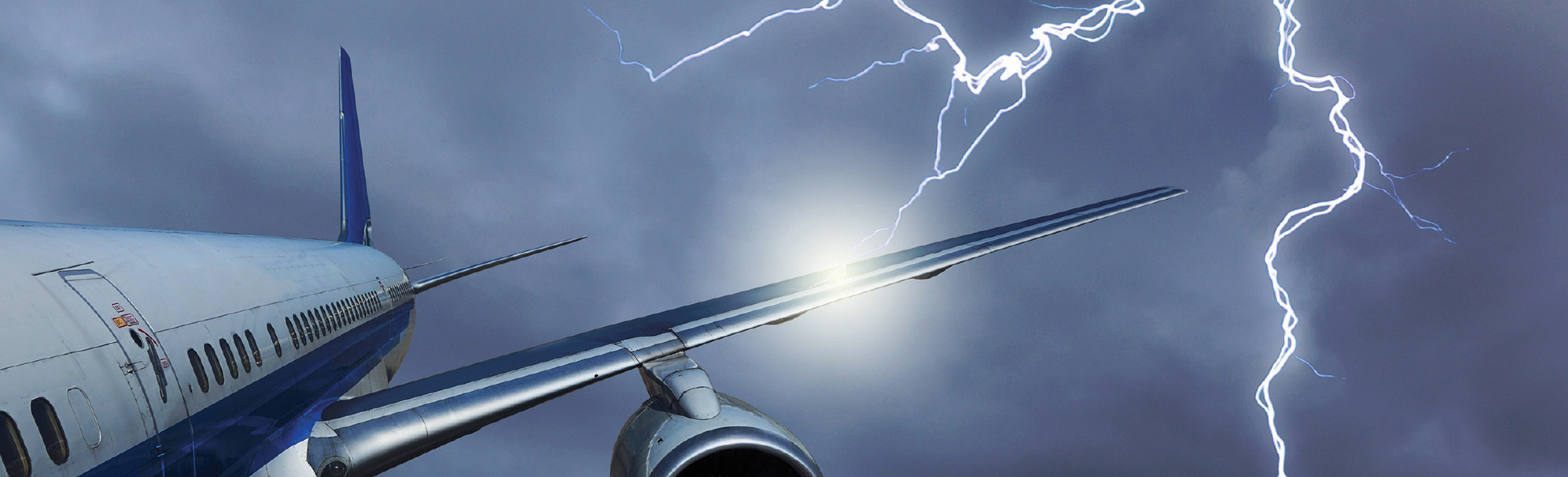 Commercial airplane flying through a stormy sky illuminated by bright lightning strikes near its wing.
